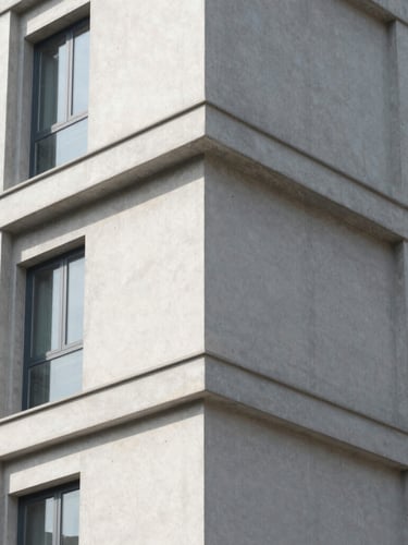 Crisp architectural detail of concrete and steel residential building corner, sharp geometric shadows, bright morning sun, desaturated cool tones
