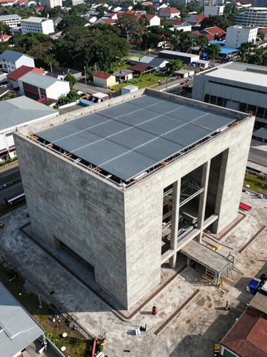 Overhead drone photograph of a completed infrastructure facility in Surabaya, large-scale concrete structure with steel roofing visible from above, natural midday light casting clean shadows across the site, surrounding urban context showing scale of the project