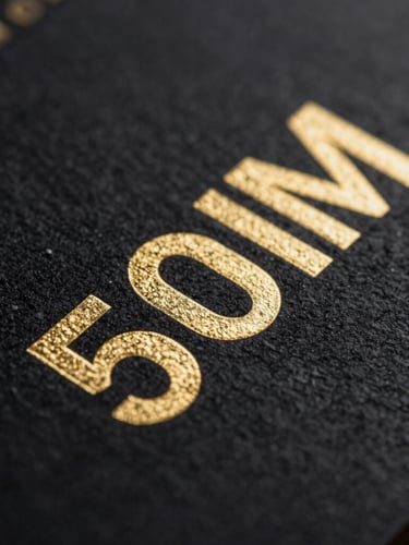 Extreme macro close-up of heavy-stock black business cards with crisp metallic gold embossed lettering, dramatic studio lighting, sharp focus, 50mm lens