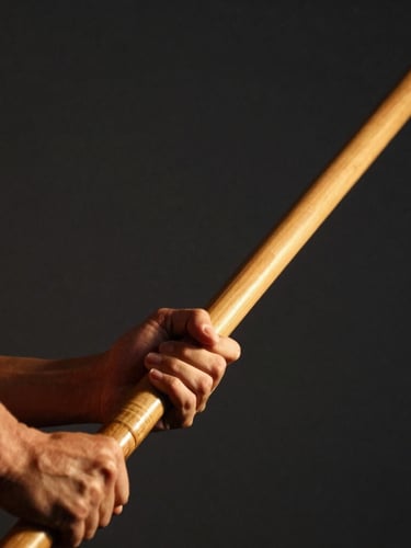 Dramatic athletic photography, low-key side lighting, close-up of hands gripping a wooden Bo staff, dark charcoal background, warm gold highlights, sharp focus