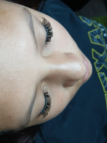 Close-up of a woman's face showing professional volume eyelash extensions with a natural curl.
