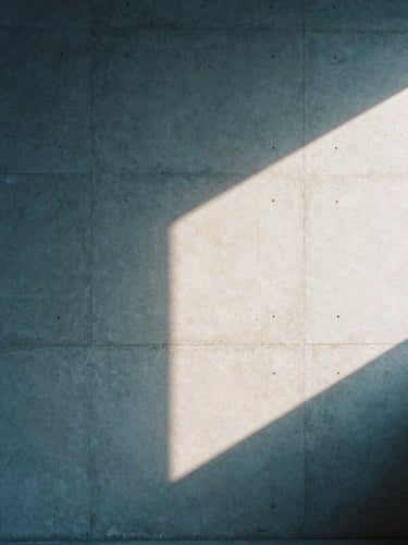 Architectural crop of a minimalist concrete studio wall with soft afternoon window light casting sharp geometric shadows, 35mm