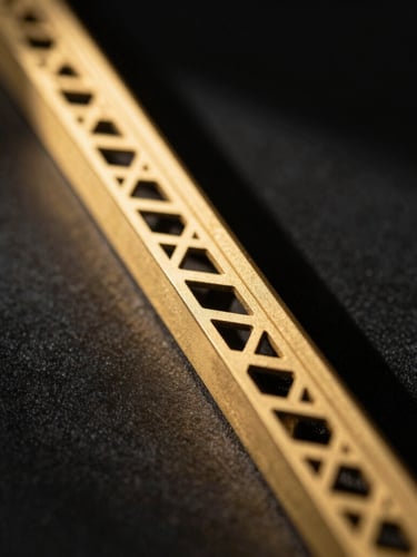 Macro close-up of a laser-cut gold metal screen edge, flawless precision CNC cut, dramatic directional sunlight casting geometric shadows on a black background, architectural 35mm photography