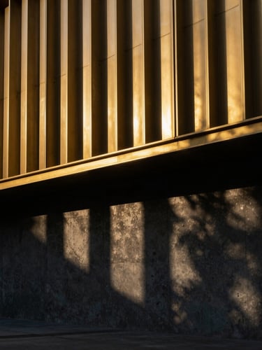Dramatic architectural photography of a golden laser-cut metal facade during golden hour, sharp geometric shadows cast on a dark concrete wall, 35mm
