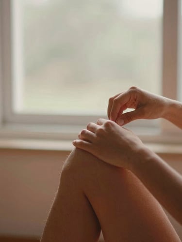 Close-up editorial photograph of Tatiane Reiner gently adjusting a student's shoulder alignment during a pose, warm natural window daylight, soft terracotta tones, shallow depth of field, 35mm film style.