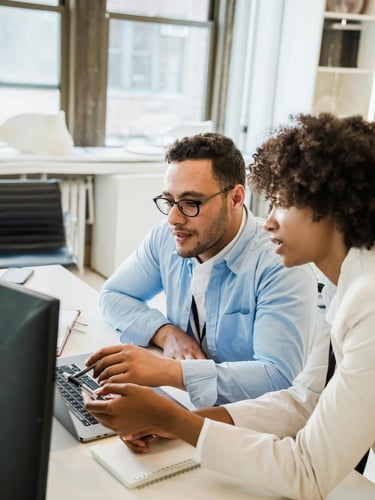 a man and woman sitting at a desk with a laptop