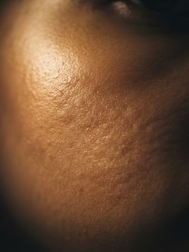 Extreme close-up macro shot of healthy, radiant skin texture under dramatic low-key studio lighting, warm gold tones, 35mm