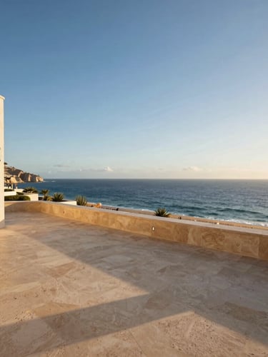 Wide-angle architectural shot of a premium villa terrace overlooking the deep blue sea in Los Cabos, warm golden-hour sunlight casting long shadows on travertine floors.