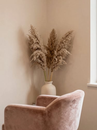 Warm aesthetic view of a clean, minimalist beauty salon corner, soft sand walls, a comfortable velvet chair, pampas grass in a ceramic vase