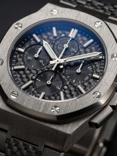 A close-up of a high-end mechanical chronograph watch, brushed titanium case, dark carbon fiber dial, low-key dramatic lighting with cool silver undertones.