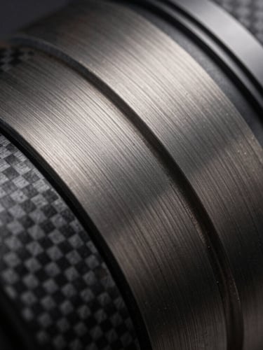 Extreme close-up of dark brushed titanium and carbon fiber textures, sharp diagonal lines, high-contrast studio lighting with cool undertones, sterile precision