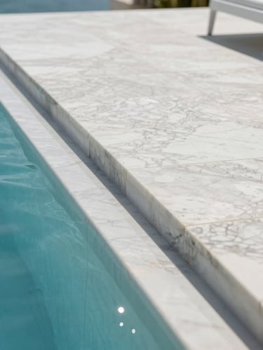Low-angle architectural close-up of a polished marble terrace kissing a luxury pool, bright coastal sunlight creating sharp specular reflections, clean lines, pristine white stone.