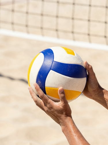 Close-up of sand-covered hands holding a professional volleyball, crisp net lines in the background, bright high-contrast sunlight, shallow depth of field, 35mm