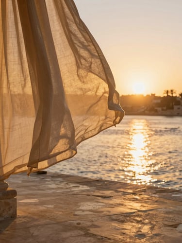 Close-up architectural detail of a luxury stone terrace overlooking the Nile at sunset, warm golden light reflecting on water, linen drapery gently blowing.