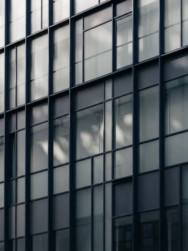 Abstract architectural details showing light filtering through glass panels, clean geometric composition, soft shadows, deep navy and muted gray tones
