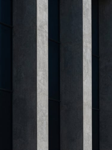 Macro architectural crop of concrete columns and glass facades, sharp geometric shadows, high-contrast minimalist photography, deep navy tones