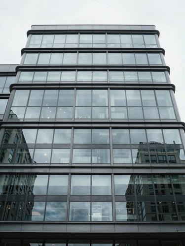 Straight-on architectural elevation of a modern glass and steel commercial building facade, overcast daylight, highly structured and technical framing.