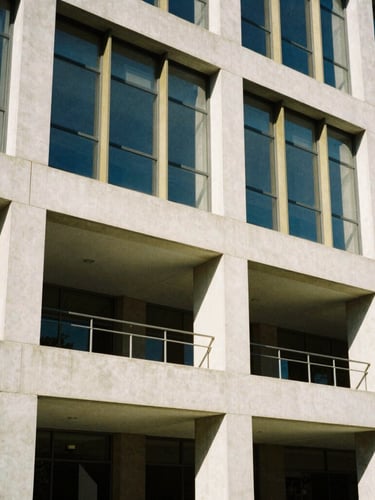 Striking architectural crop of modern concrete and glass campus building facade, bright natural daylight, geometric shadows, 35mm editorial photography.
