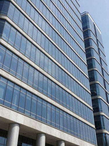 Fachada exterior do edifício de escritórios corporativos modernos em Luanda, arquitetura contemporânea de vidro e betão sob luz solar brilhante, tons azuis corporativos limpos.