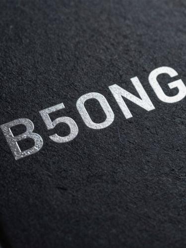 Extreme close-up of a physical thriller book cover with embossed silver foil text on a dark, textured matte paper background, moody shadows