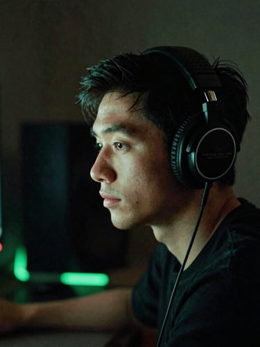 Focused creator wearing studio headphones in a dimly lit production space, soft screen-glare illuminating their face, neon green ambient glow, moody 35mm photography