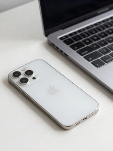 A crisp close-up of a clean silver iPhone and space gray MacBook on a minimalist white oak desk, bright natural morning light, premium Apple aesthetic