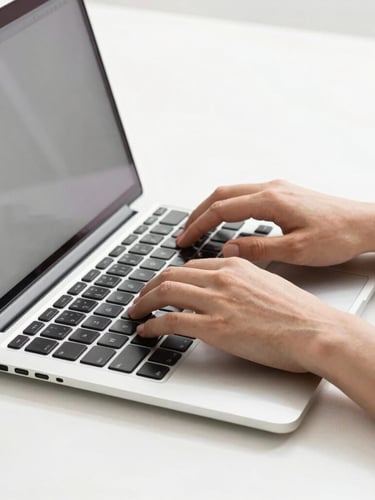 Close-up of hands typing on a sleek silver laptop, crisp shadows, bright high-key studio lighting, organized minimal workspace.