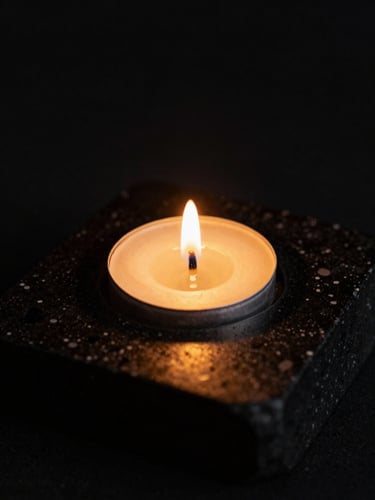 Macro detail of warm golden candle light reflecting on black obsidian stone, soft shadows, 35mm photography