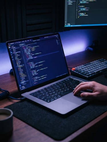 Close-up of a clean modern workspace with a laptop showing code, subtle electric blue and violet ambient lighting, dark moody tech photography style, 35mm lens