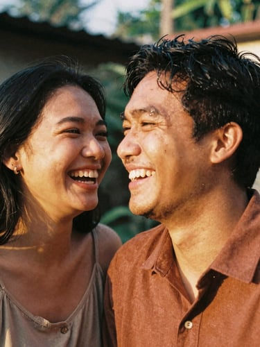 Intimate close up of a young Indonesian couple laughing together in warm golden hour sunlight, outdoor backyard setting, shallow depth of field, 35mm film texture