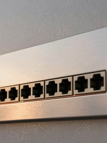 Close-up of a sleek architectural metal wall plate with integrated network ports, warm copper accent lines, soft twilight lighting reflecting off the metallic surface