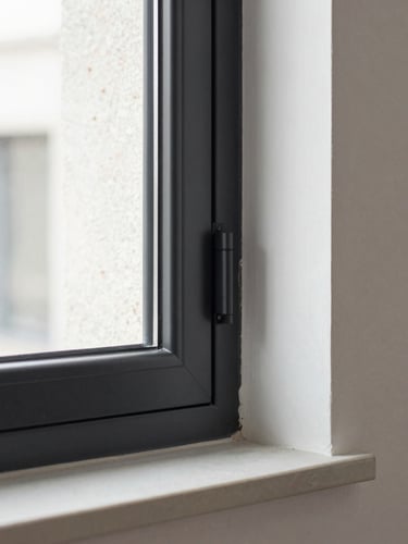 Plan detalle de un perfil de ventana de aluminio negro mate encastrado en un muro de hormigón visto, luz natural limpia y neutra, enfoque nítido, fotografía arquitectónica