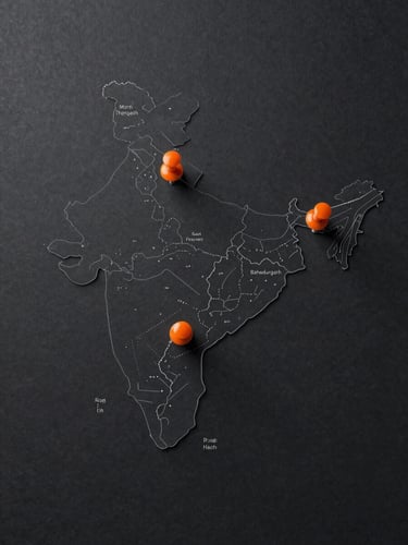 Overhead flat-lay map of India rendered as a clean industrial schematic on dark charcoal surface, three bright orange pin markers placed at Gujarat (Morbi/Thangadh region) and Haryana (Bahadurgarh region), minimal line-art style, no text labels visible, clinical studio lighting from above, wide landscape crop with generous right-side bleed
