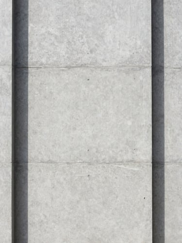 Clean straight-on architectural photography of a modern concrete facade with sharp shadows, bright diffused daylight, neutral gray tones, 35mm.