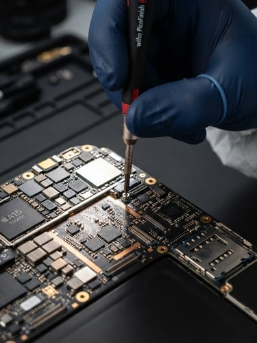 Extreme macro shot of a clean-room technician using a precision screwdriver on an iPhone motherboard, bright strobe lighting reflecting off copper circuits