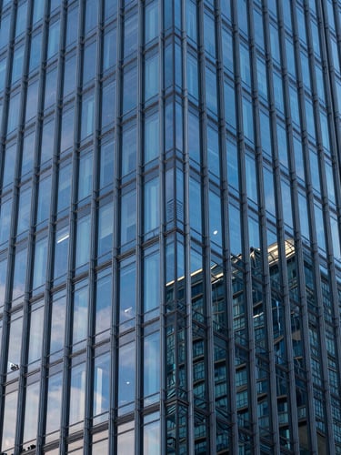 High-angle architectural detail of a modern steel and glass skyscraper facade, cool blue-hour lighting, crisp reflections.