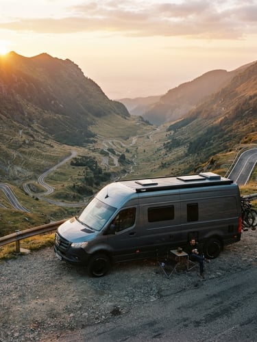 Cinematic side profile of a sleek grey campervan parked on a narrow cliffside road overlooking the Transfăgărășan at sunrise, golden light reflecting off polished paint, 35mm