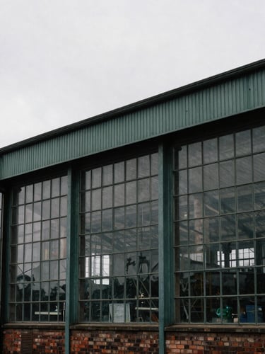 Wide environmental shot of a converted industrial warehouse in Lancashire, large steel windows, overcast daylight, moody editorial photography, desaturated tones.