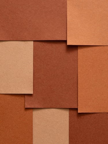Composition abstraite de papiers texturés superposés dans les tons terracotta et ocre, lumière rasante révélant le grain de la matière.