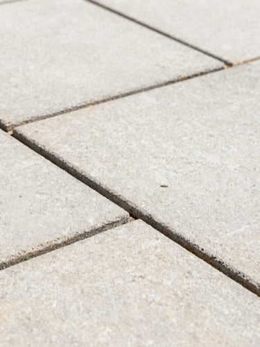Close-up macro shot of crisp, freshly repointed mortar joints between clean sandstone patio slabs, bright natural daylight, sharp focus on the texture of the stone