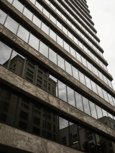 Wide architectural perspective of a modern corporate building facade in São Paulo, sharp concrete lines, overcast daylight, soft reflection on glass panels.