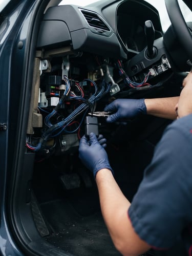 Professional GPS installer mounting a tracking device under a car dashboard, clean daylight, technical hands-on shot, 35mm lens
