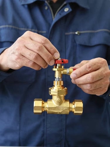Medium close-up of a professional technician in a clean navy uniform adjusting a high-pressure brass valve, bright natural daylight, technical precision, sharp focus.