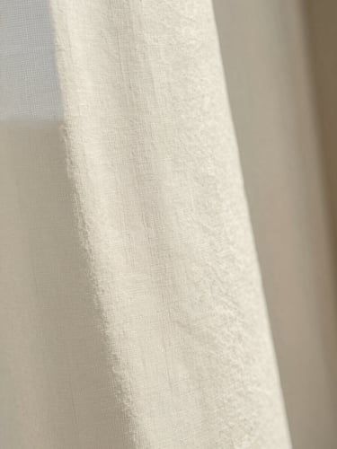 Portrait-oriented macro photograph of natural linen paper with delicate blind debossing, soft morning window light, gentle shadows, warm editorial style.