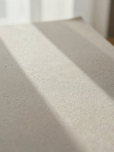 Close-up of textured handmade paper with delicate blind debossing under soft morning window light, neutral tones