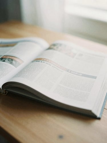 Close-up of a thick editorial journal open on a wooden table, soft shadows, warm morning light