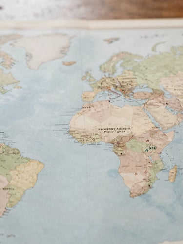 Mapa global sutil de puntos de despliegue de la red de Primeros Auxilios Psicológicos, con enfoque en manos de voluntarios señalando ubicaciones, luz natural difusa.