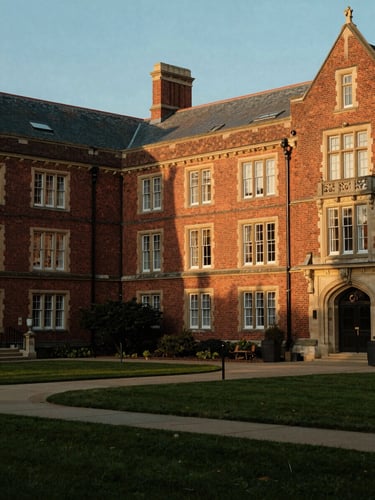 Warm editorial photography of a prestigious boarding school courtyard at golden hour, historic brick architecture, soft natural light, 35mm