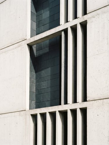 Architectural close-up of a modern concrete facade with sharp geometric shadow-play, soft north-facing daylight, high contrast slate and white tones, 35mm