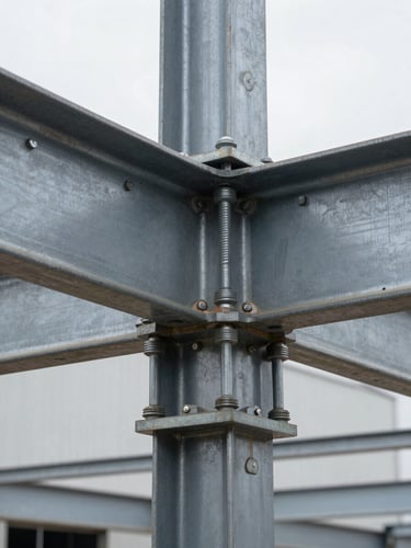 Close-up documentary shot of a steel structural connection on a completed industrial building — high-tensile bolt group in a gusset plate, mill-scale steel surface with construction markings, overcast available light showing material texture and precision fit, no people, extreme foreground detail filling the frame